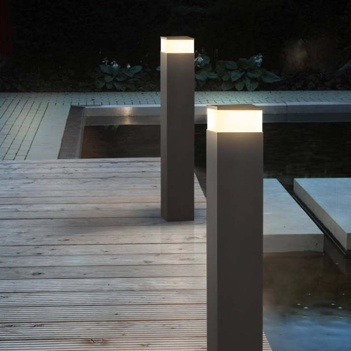 Zwei hohe schwarze Pollerleuchten mit warmweißem Licht auf einem Holzsteg neben einem dunklen Wasserbecken. 8