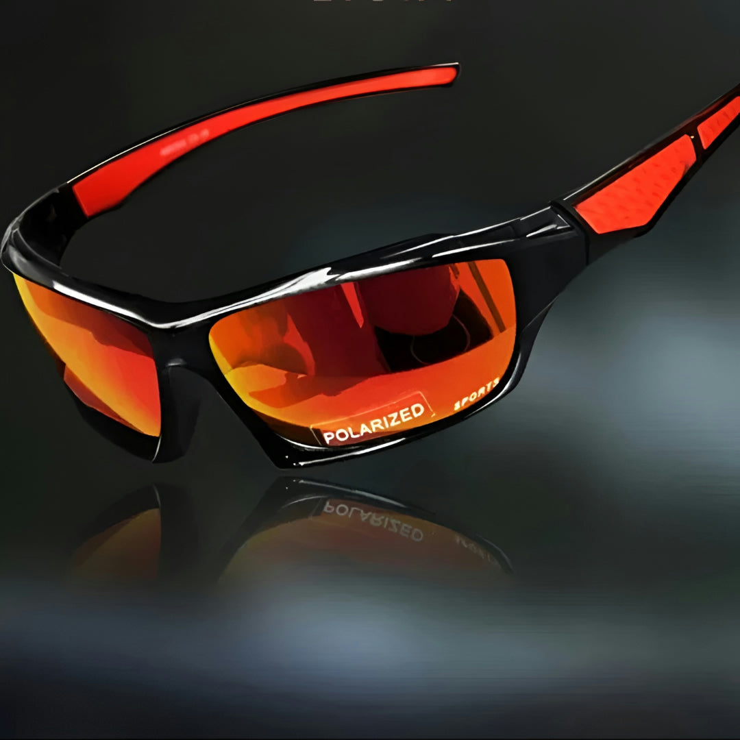 Sportbrille mit orange verspiegelten Gläsern und roten Bügelakzenten, schräg vor dunklem Hintergrund mit Spiegelung 6