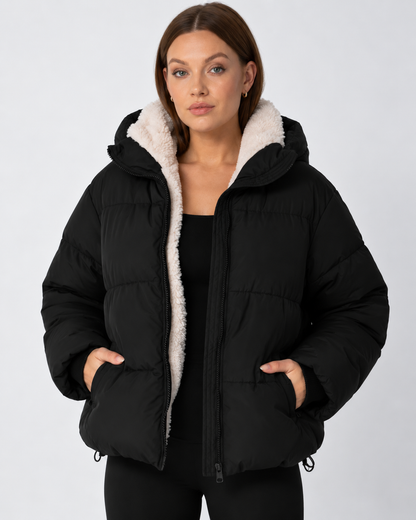 Schwarze Steppjacke offen getragen, cremefarbenes Teddyfutter am Kragen, Hände in den Taschen 11