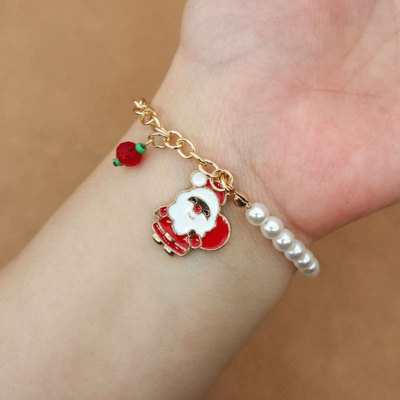 Armband mit Weihnachtsmann-Anhänger, Perlen und Erdbeer-Detail, goldfarben, festlich.