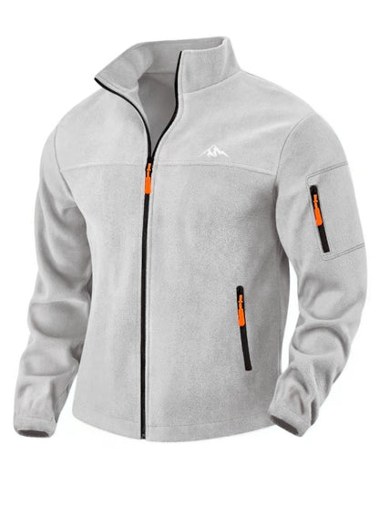 Hellgraue Fleecejacke von vorn mit Stehkragen, orangen Reißverschlussziehern, Ärmeltasche und kleinem Bergmotiv auf der 4