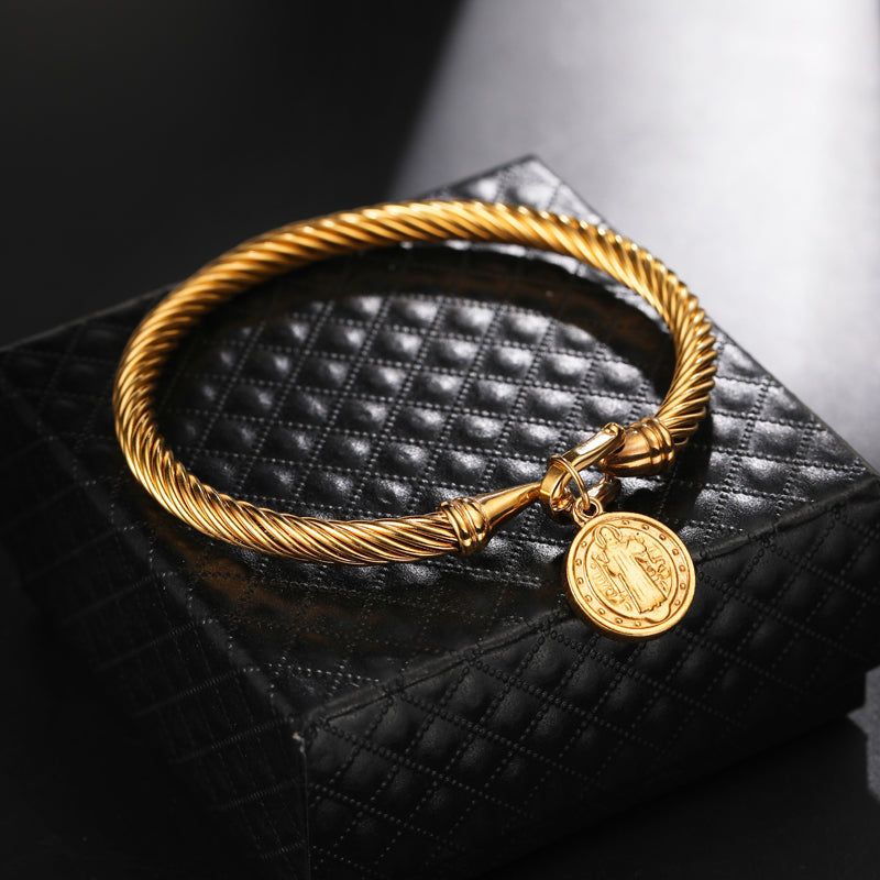 Goldenes Armband mit Anhänger, gedrehtes Design, auf schwarzem Hintergrund, Schmuckaccessoire.