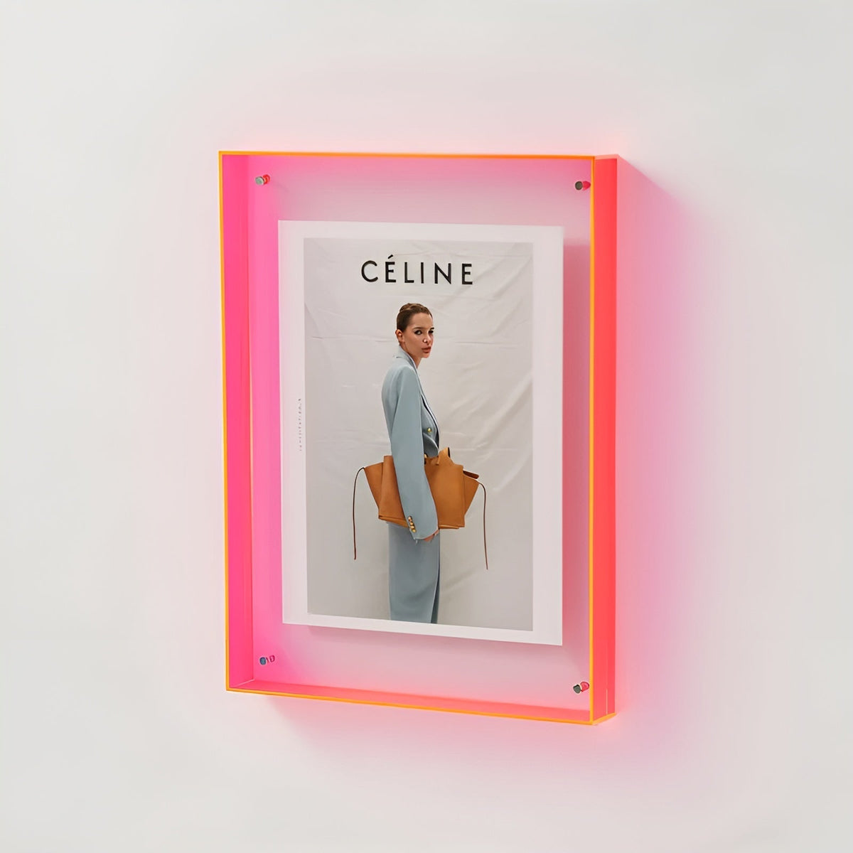 Wandmontierter Acrylrahmen in leuchtendem Neonpink mit gerahmtem Modeporträt einer Frau mit brauner Tasche. 18