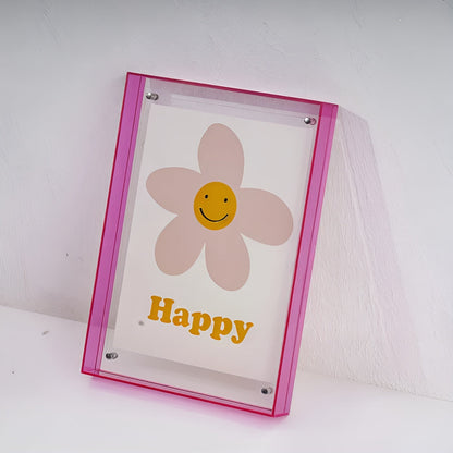 Pinker Acrylrahmen lehnt an einer Wand, darin der Druck einer lächelnden Blume mit gelbem Schriftzug. 19