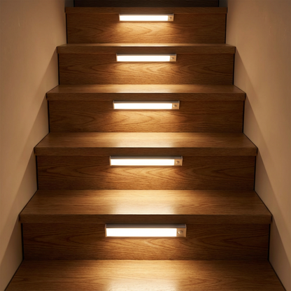 Fünf Leuchtleisten an den Stufenfronten einer Holztreppe, die jede Stufe mit warmem Licht beleuchten. 2