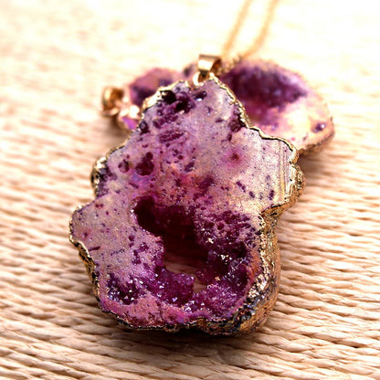 Lila Achat-Anhänger mit goldener Fassung auf geflochtener Oberfläche, Schmuck, Edelstein, elegant.