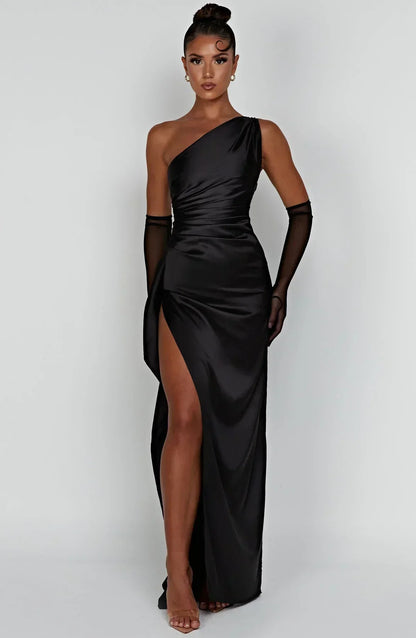Frau in schwarzem, schulterfreiem Maxikleid mit hohem Schlitz und transparenten Handschuhen.