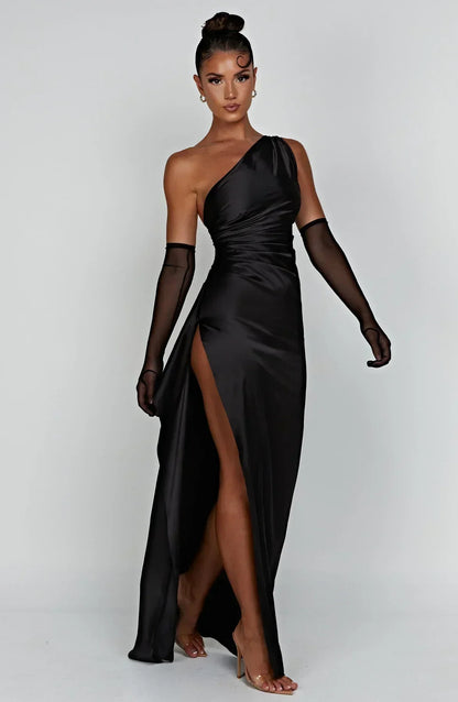 Frau in schwarzem, einarmigem Maxi-Kleid mit hohem Schlitz und transparenten Handschuhen.