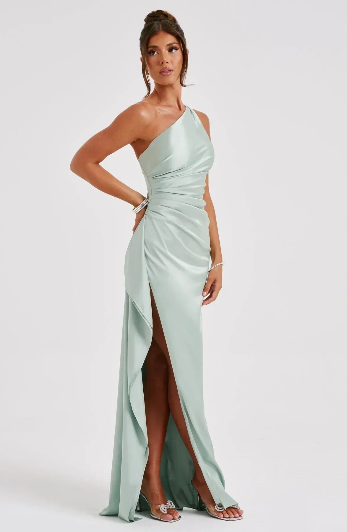 Frau in einem schulterfreien, salbeigrünen Maxikleid mit hohem Schlitz, elegant und modern.
