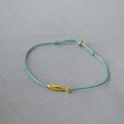 Grünes Armband mit gelbem Fischanhänger, minimalistisches Schmuckdesign, handgefertigt.