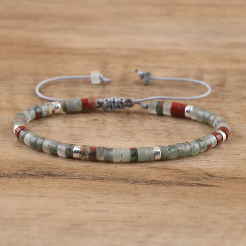 Armband aus Natursteinperlen, grün und rot, verstellbar, handgefertigt, auf Holzoberfläche.