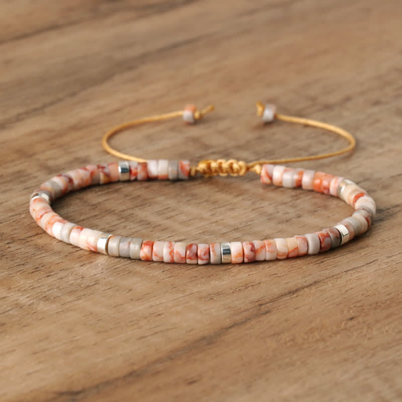 Armband aus Natursteinperlen, verstellbar, beige und orange, handgefertigt, auf Holzoberfläche.