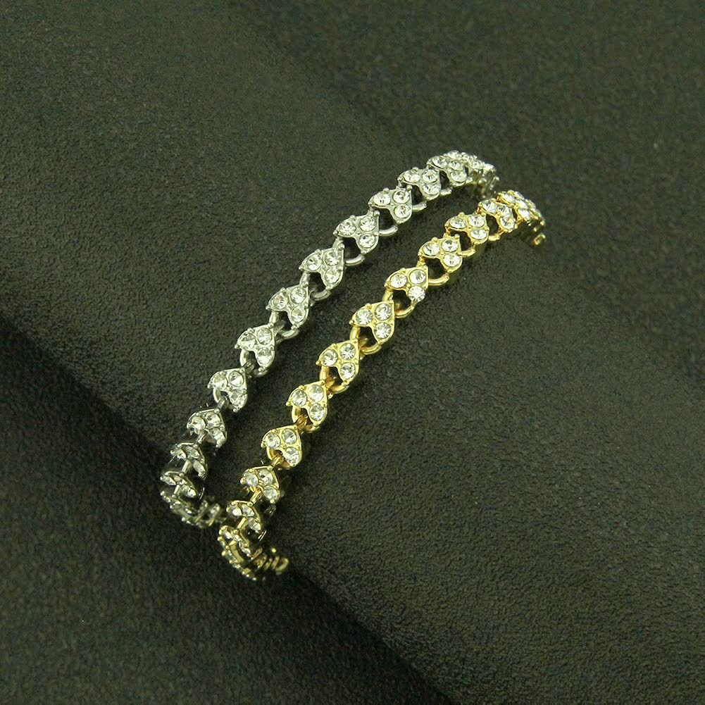 Zwei Armbänder, silber und gold, mit Herzdesign und Strasssteinen auf schwarzem Hintergrund.