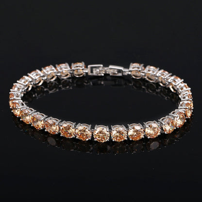 Silbernes Tennisarmband mit runden, champagnerfarbenen Zirkonia-Steinen auf schwarzem Hintergrund.