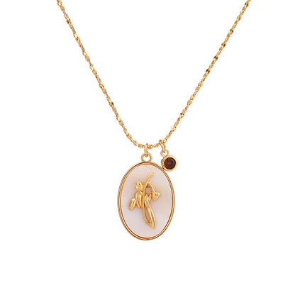 Goldene Halskette mit ovalem Anhänger, Blumenmotiv, weißer Hintergrund, eleganter Schmuck.
