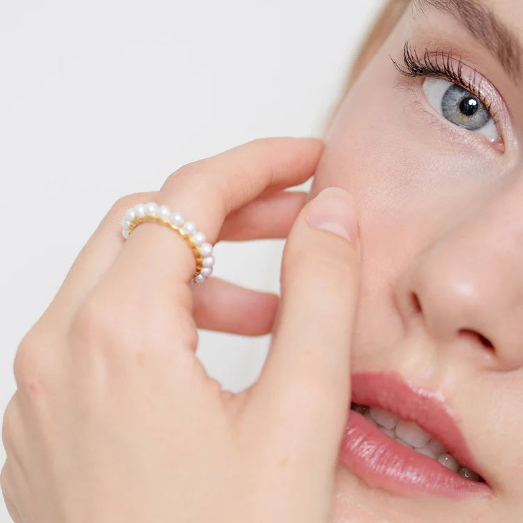 Frau mit Perlenring, Nahaufnahme, eleganter Schmuck, Modeaccessoire, stilvoll, minimalistisch.