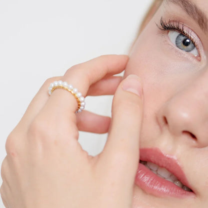 Frau mit Perlenring, Nahaufnahme, eleganter Schmuck, Modeaccessoire, stilvoll, minimalistisch.