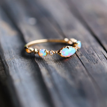 Goldener Opalring mit funkelnden Steinen auf Holzoberfläche, eleganter Schmuck, Damenaccessoire.