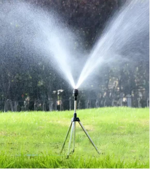 Rasensprenger auf Stativ, bewässert grünen Rasen, Gartenbewässerung, Sommer, effizient, langlebig.