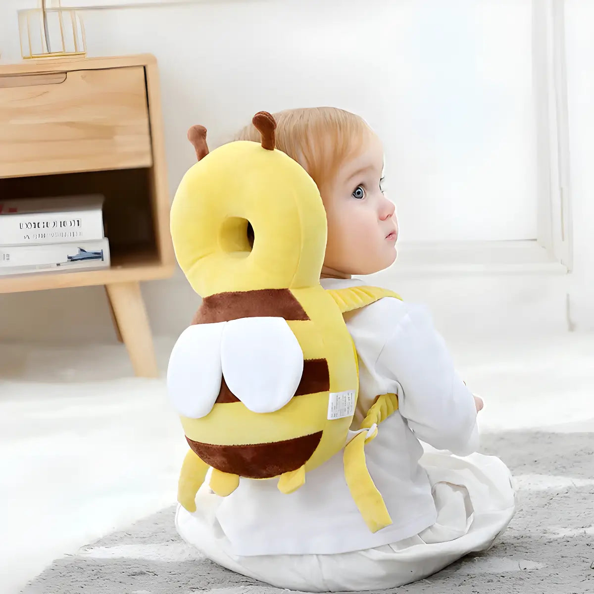 Kleinkind mit gelbem Bienen-Rückenschutzkissen, Sicherheitskissen für Babys, auf Teppich.