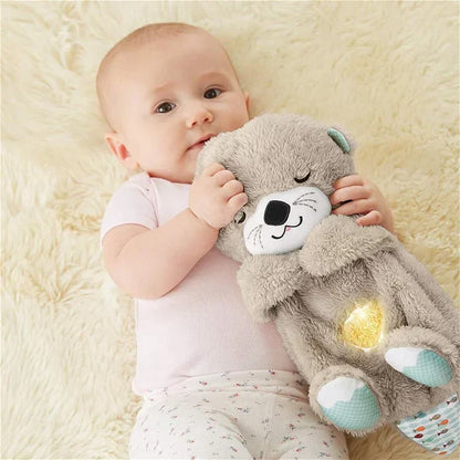 Baby mit Fisher-Price Plüschotter, grau, leuchtend, Musikspielzeug, auf Teppich liegend.