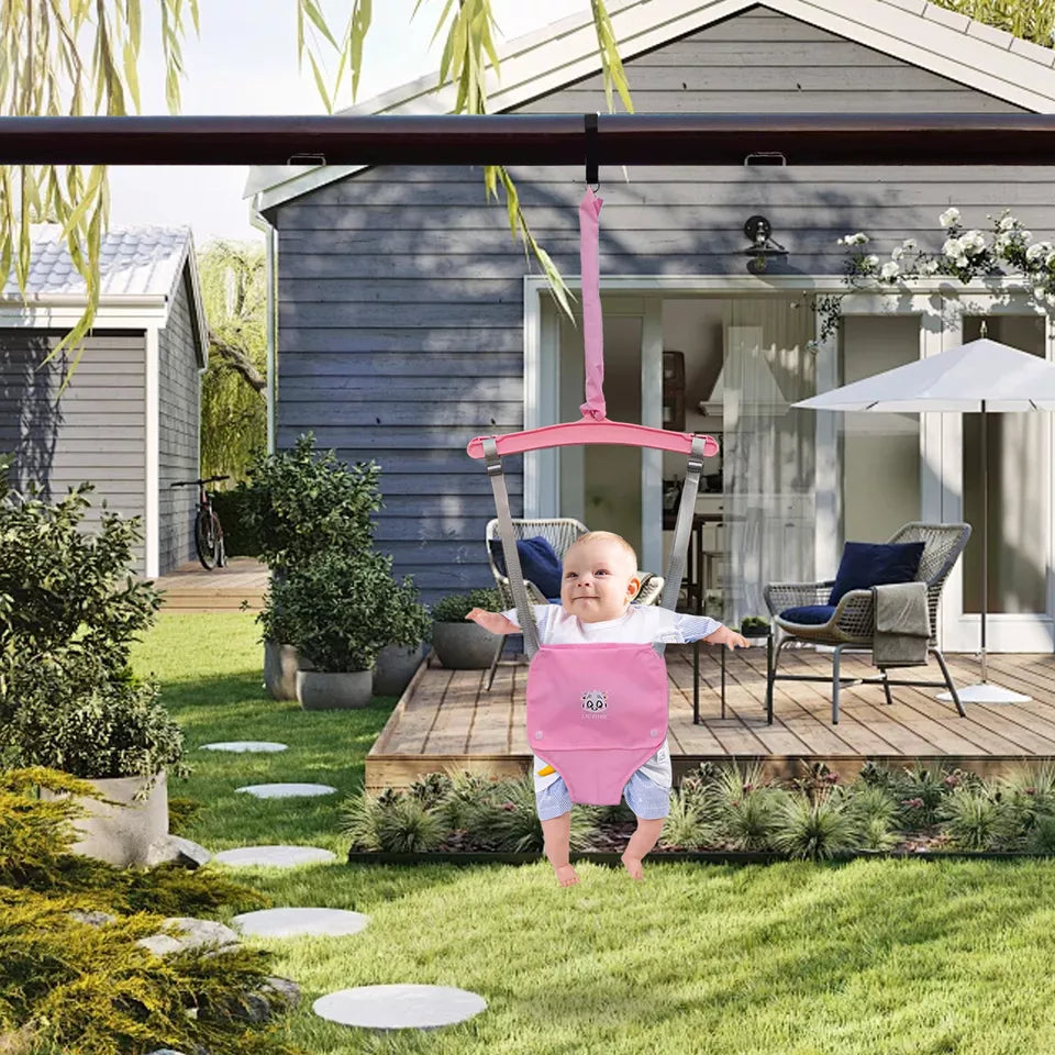 Baby in rosa Türhopser im Garten vor modernem Haus, Holzterrasse, Gartenmöbel, Sonnenschirm.