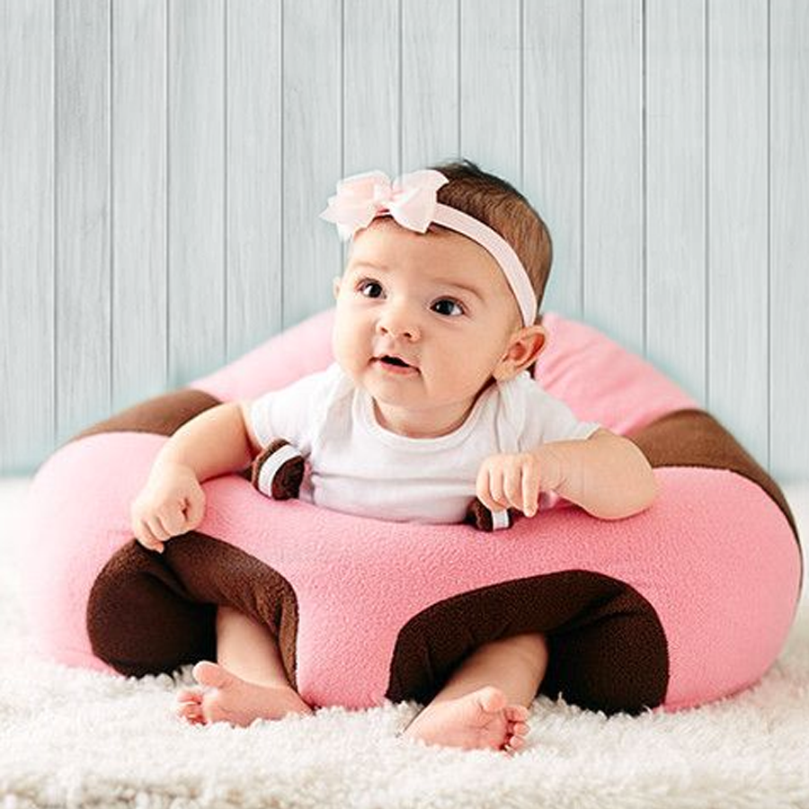 Baby in rosa und braunem Sitzkissen, Holz-Hintergrund, süßes Baby, bequemes Sitzkissen.