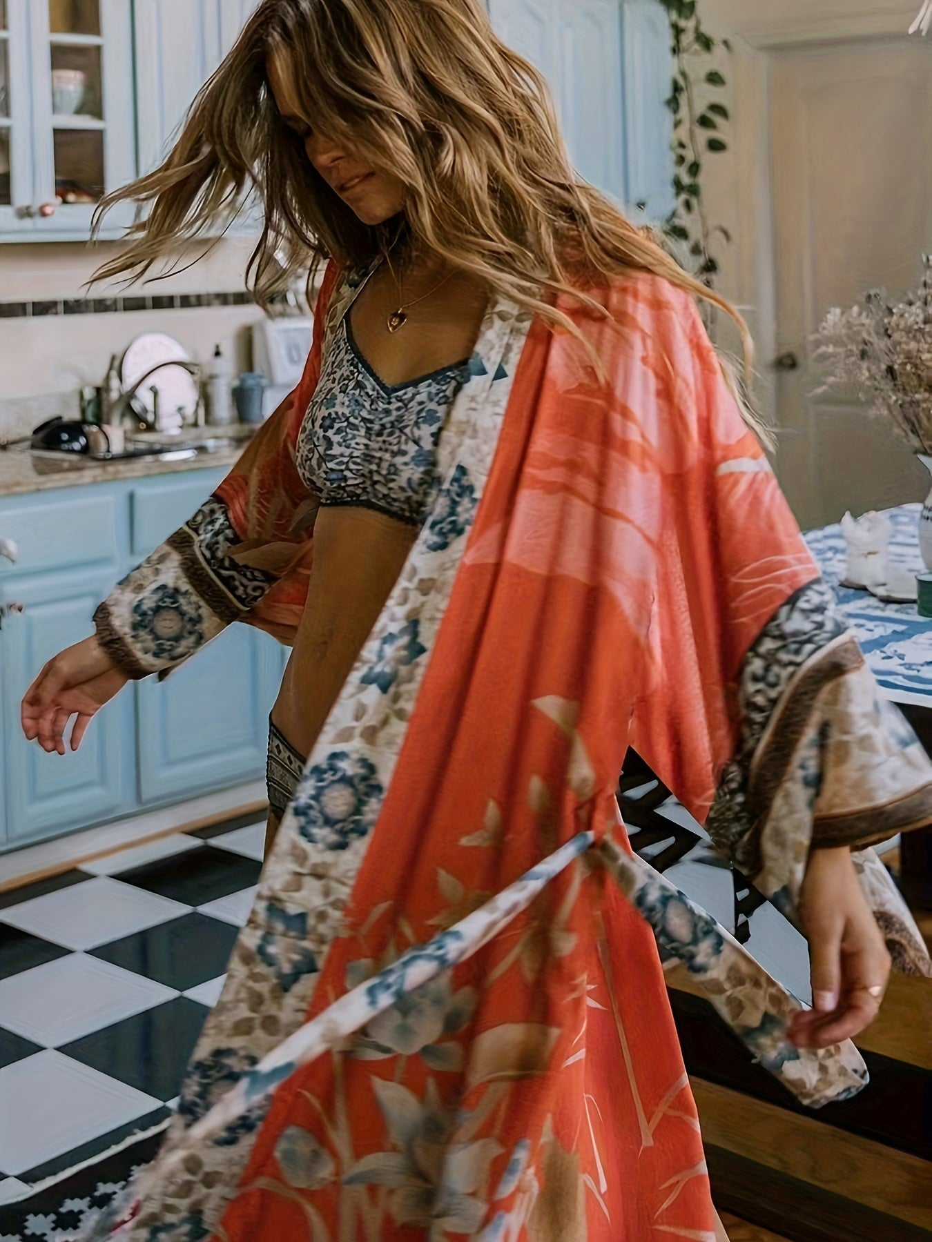 Frau in rotem Kimono mit Blumenmuster in Küche, modische Damenbekleidung, Boho-Stil.