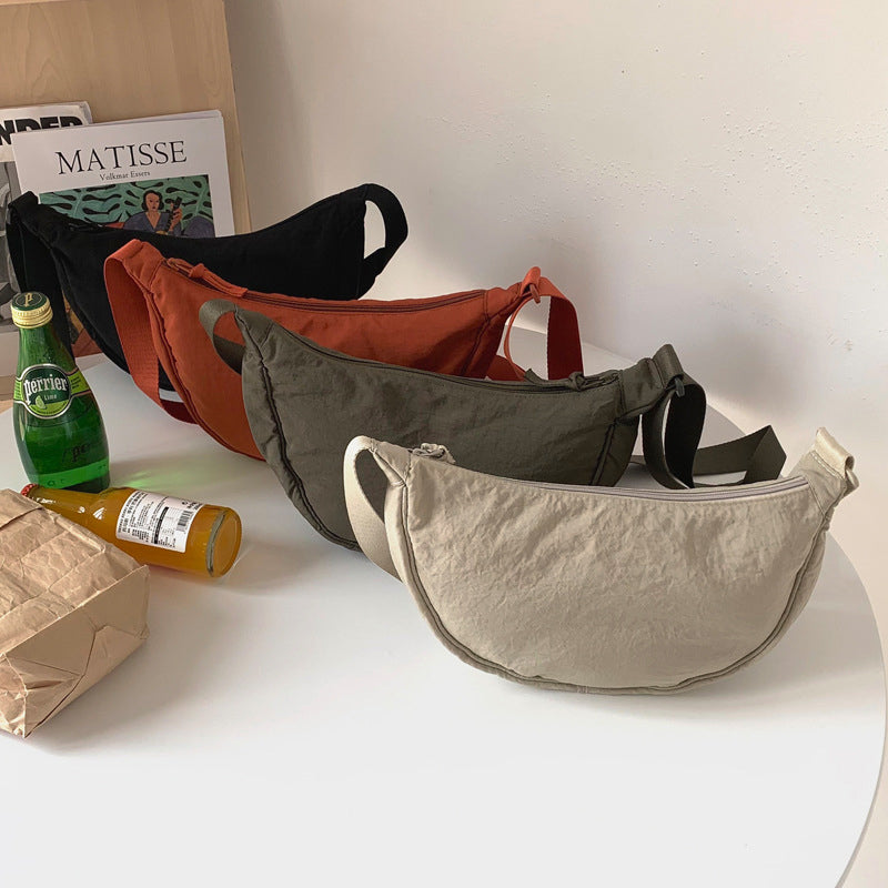 Vier Gürteltaschen in Beige, Grün, Rot auf Tisch, neben Getränken und Zeitschriften.