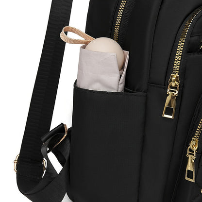 Detailansicht der Seitentasche des schwarzen Rucksacks, in der ein kleiner Schirm steckt 10
