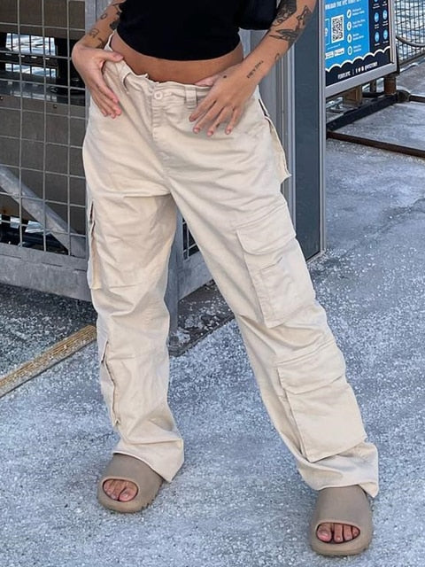 Frau in beigen Cargohosen und Sandalen, urbaner Hintergrund, lässiger Streetwear-Look.