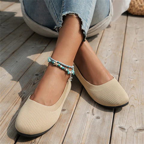 Beige Damen-Ballerinas aus Stoff, lässig, bequem, mit blauer Perlenkette, auf Holzterrasse.