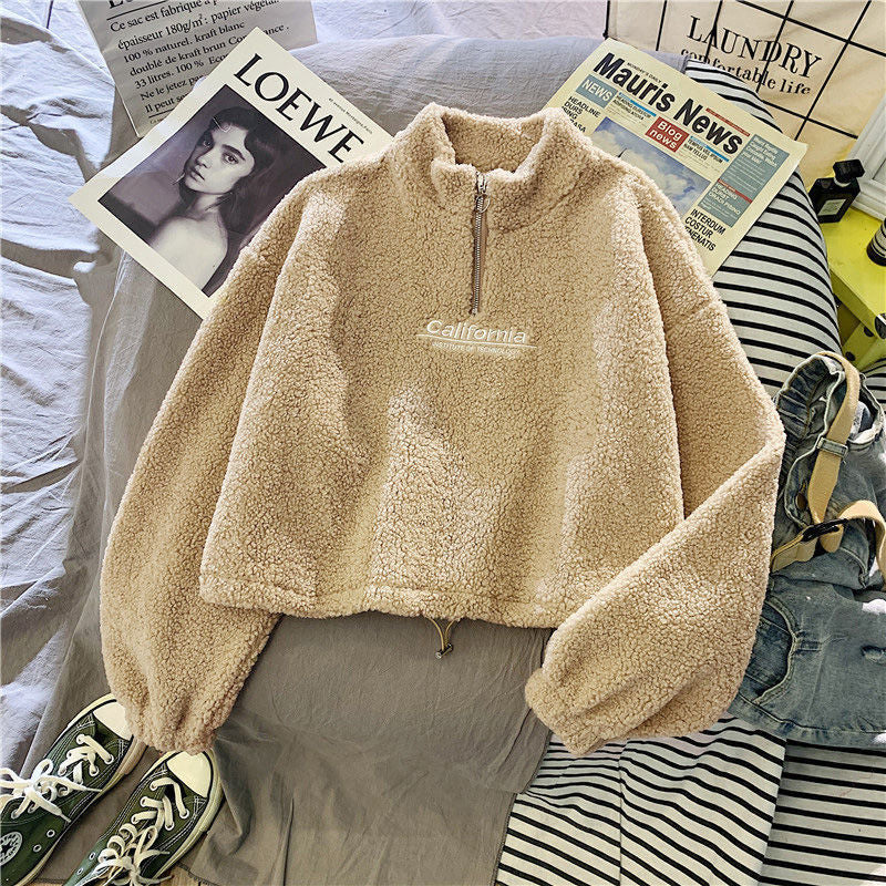 Beige Teddy-Fleece-Pullover mit Reißverschluss und "California"-Schriftzug auf Bett.