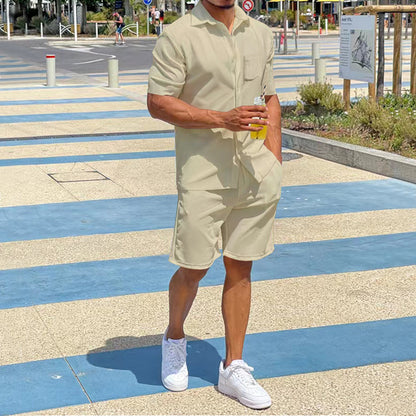 Mann in beigem Kurzarm-Overall mit Getränk, weiße Sneaker, Sommermode, urbaner Hintergrund.