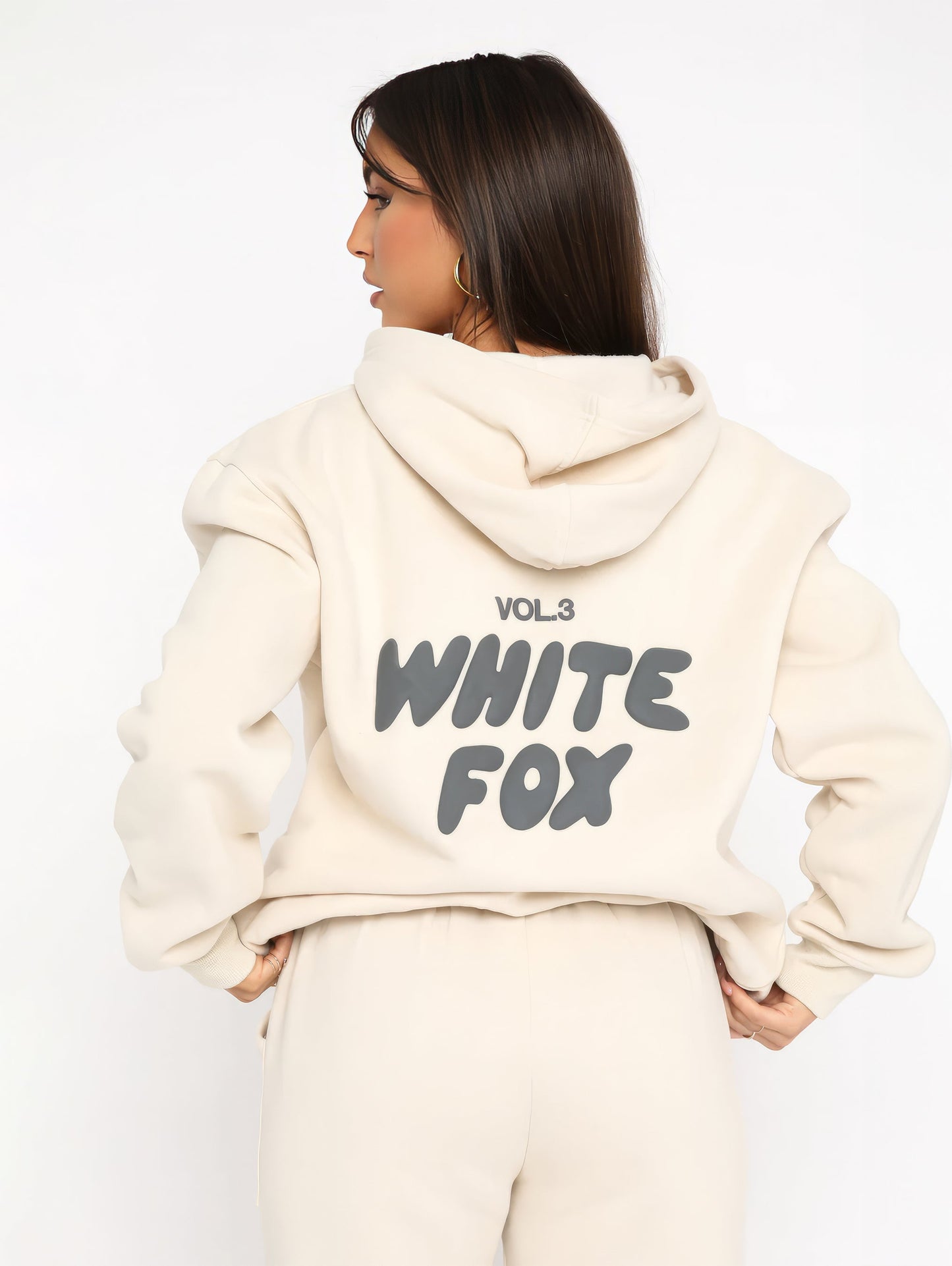 Frau in cremefarbenem Hoodie mit "White Fox" Aufdruck, Kapuze, lässiger Stil.