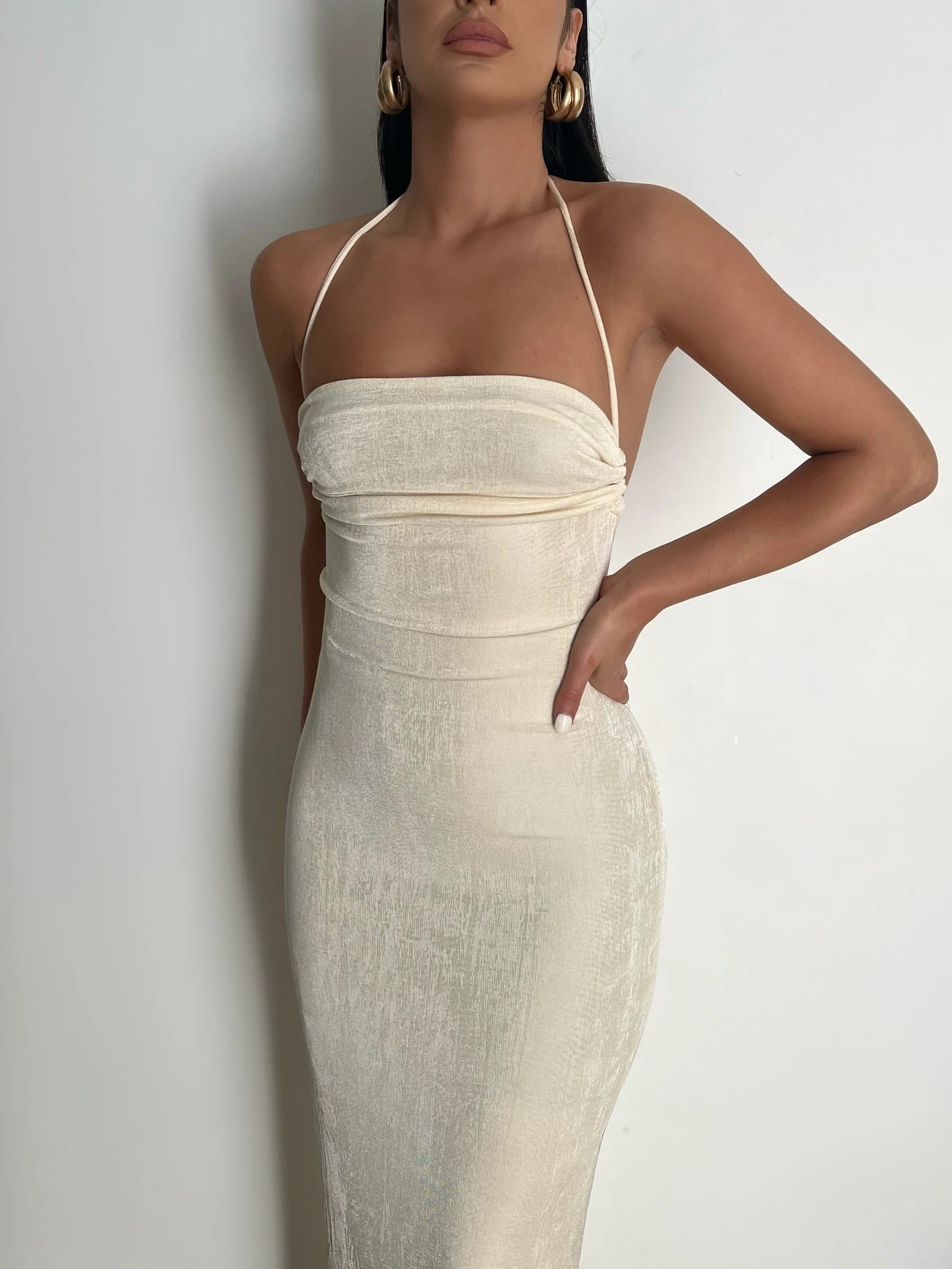 Frau in cremefarbenem, schulterfreiem Kleid, elegantes Abendmode-Outfit, minimalistischer Stil.