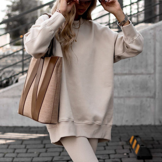 Frau in beigem Oversize-Pullover mit brauner Handtasche, lässiger Herbstlook, Modeaccessoires.