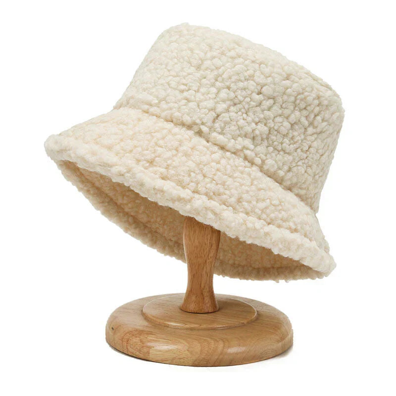 Beiger Damen-Bucket-Hut aus Fleece auf Holzständer, modisch und warm.