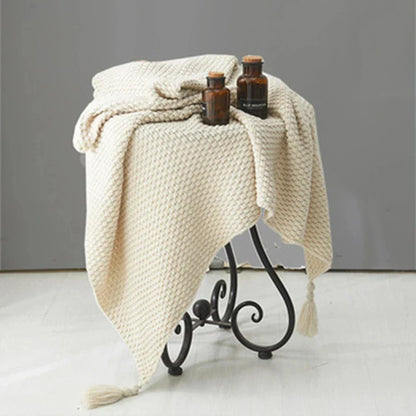 Beige Strickdecke auf Metallhocker, dekoriert mit braunen Glasflaschen, Wohnzimmerdekoration.