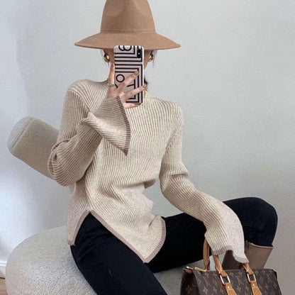 Frau mit beigem Strickpullover, braunem Hut, Smartphone und Designer-Handtasche.