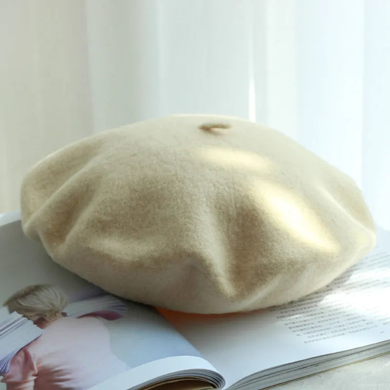 Beige Woll-Baskenmütze auf offenem Buch, stilvolles Accessoire, modisch, elegant.
