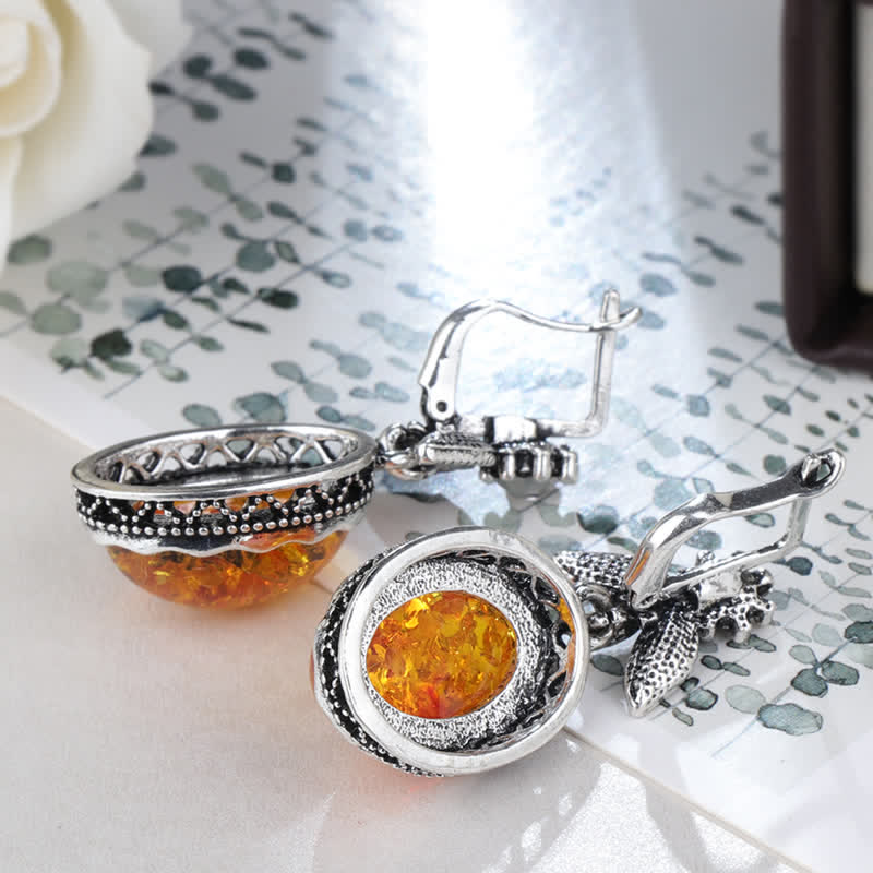 Silberne Ohrringe mit Bernstein, florales Design, eleganter Schmuck, auf Tisch liegend.