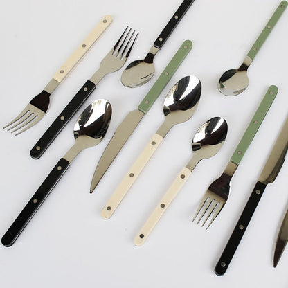 Besteckset aus Edelstahl mit schwarzen, weißen und grünen Griffen, modern, stilvoll, langlebig.