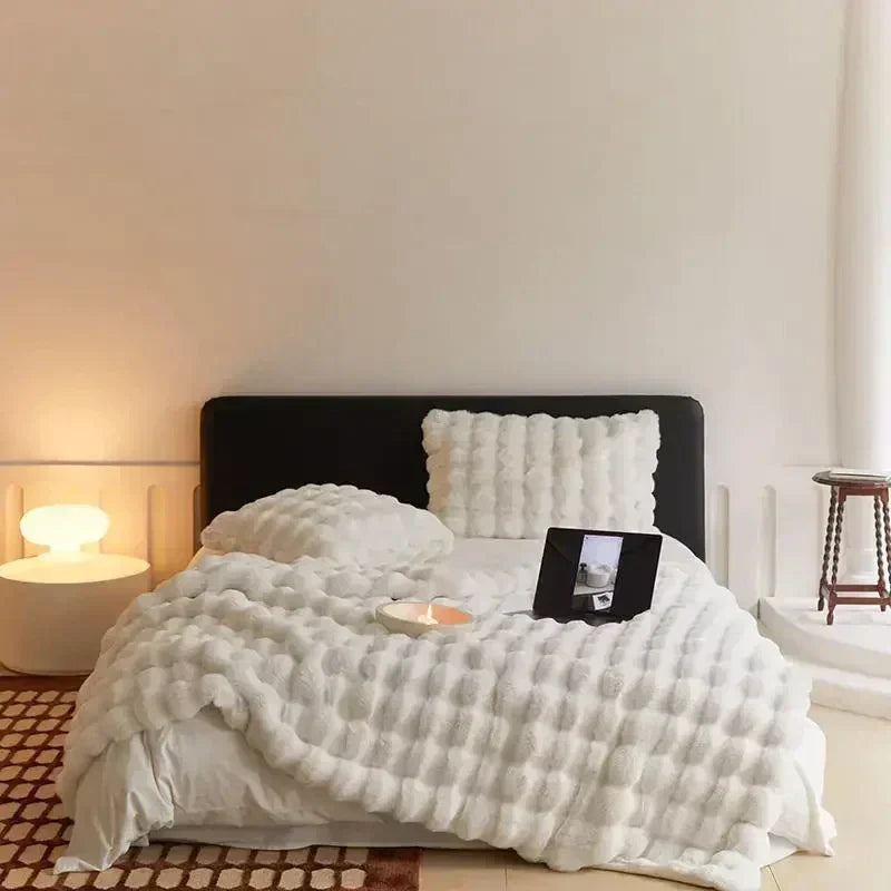 Gemütliches Schlafzimmer mit weißer Bettdecke, Kissen, Nachttischlampe und Tablet auf dem Bett.