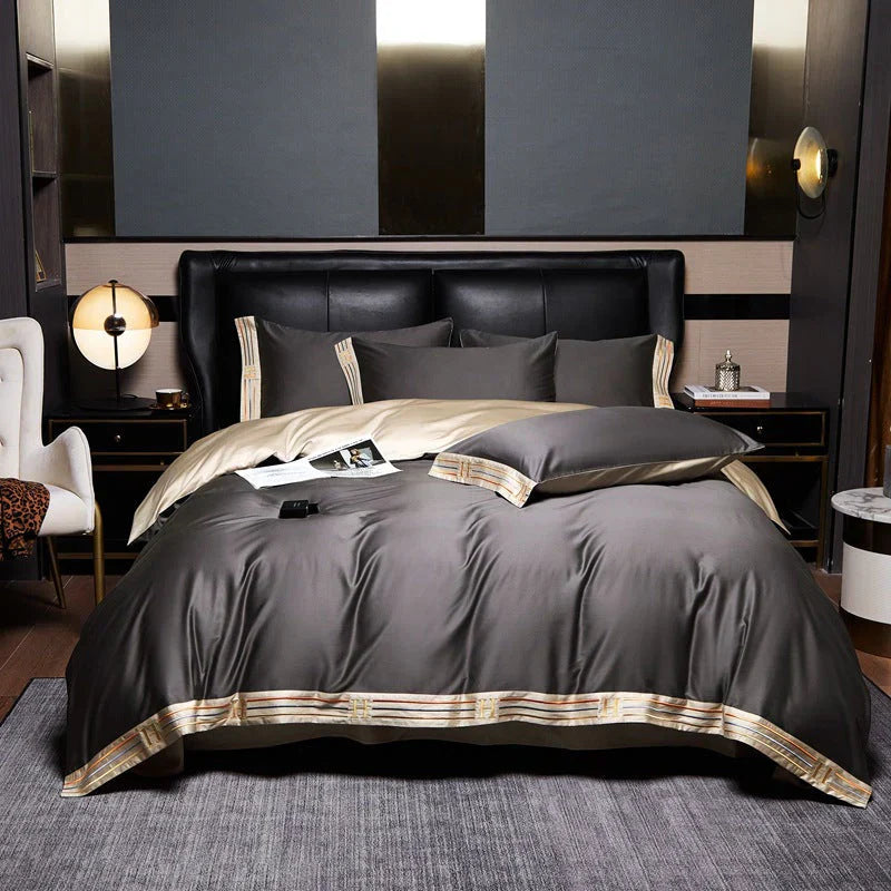 Luxuriöse graue Bettwäsche-Set aus Satin mit goldenen Akzenten auf einem modernen Doppelbett.