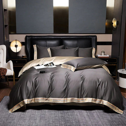 Luxuriöse graue Bettwäsche-Set aus Satin mit goldenen Akzenten auf einem modernen Doppelbett.