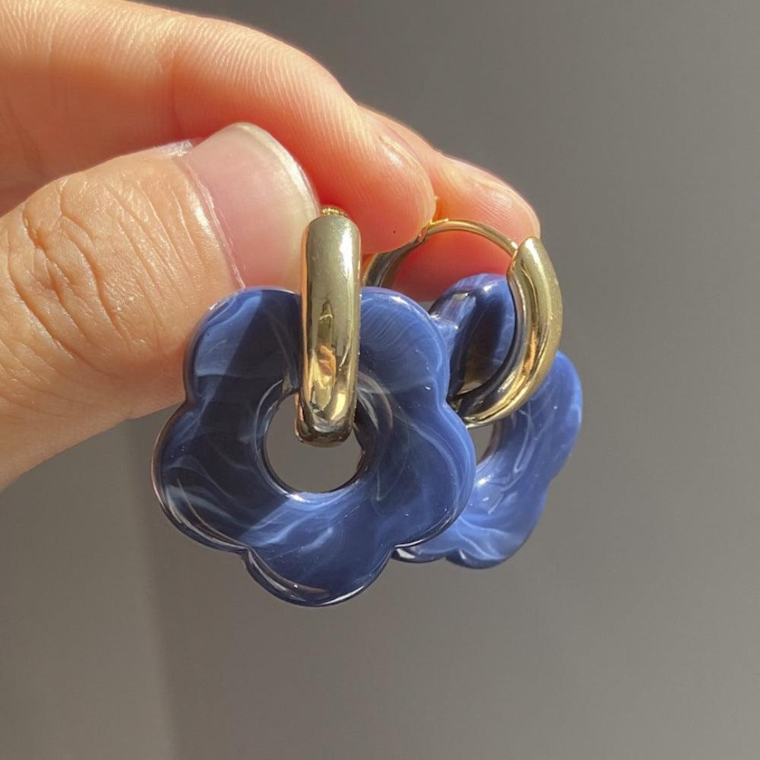 Goldene Creolen mit blauen Blumenanhängern, modische Ohrringe, Schmuckaccessoire.