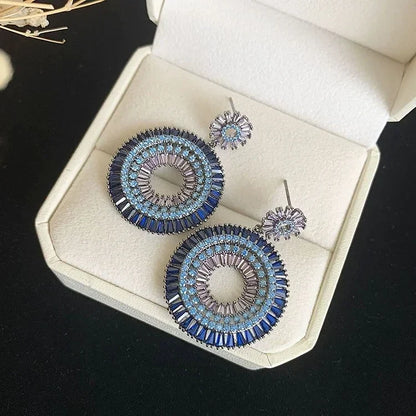 Blaue runde Ohrringe mit Kristallen in Schmuckschatulle, elegantes Design, Damenaccessoire.