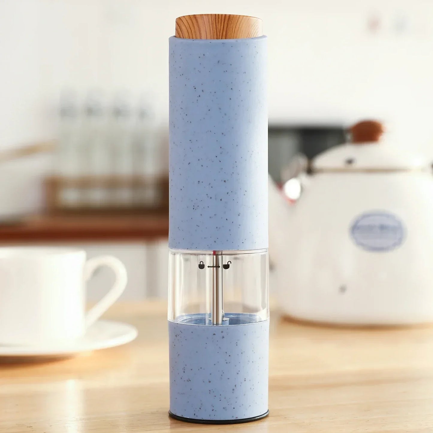 Blaue elektrische Pfeffermühle aus Kunststoff mit Holzdeckel auf Küchentisch.