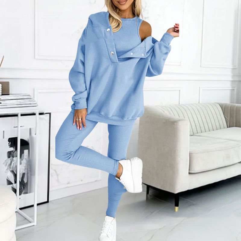 Frau in hellblauem Jogginganzug, Schulterfrei, moderne Wohnzimmerkulisse, weiße Sneaker.
